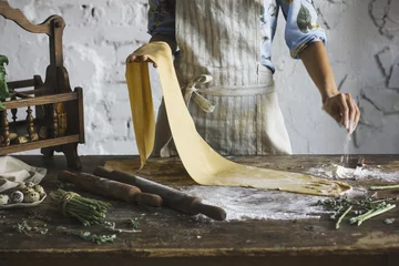 Küchenrückwand glas motiv Young woman in the apron preparing the dough for homemade pasta at rustic kitchen © Galina Zhigalova
