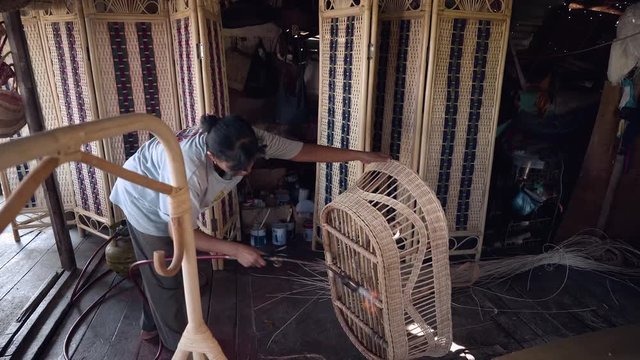 Indonesian woman treating rattan basket with fire in wicker furniture workshop. Shot with Sony a7s and Atomos Ninja Flame
