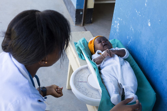 Nurse weighing baby in clinic. Kenya, Africa