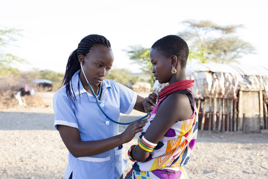Nurse examing female patient in rural village.