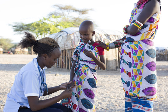 Nurse examing young girl in rural village. Kenya, Africa.
