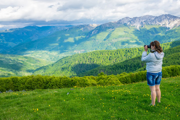 Naklejka premium The girl photographer shoots the top of the mountain Komovi. Montenegro.