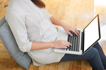 Young woman sitting on floor with laptop in library, education and technology concept.