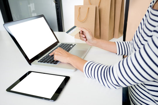 Closeup of happy young woman holding credit card inputting card information while and using laptop computer at home. Online shopping concept.
