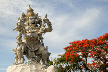 monkey king statue with red flowers at Uluwatu temple, Bali