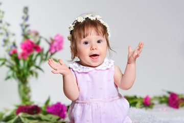 Little girl in a pink dress sitting with a bouquet of pink flowers