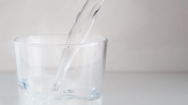 water pouring into glass on white background. slow motion. copy space