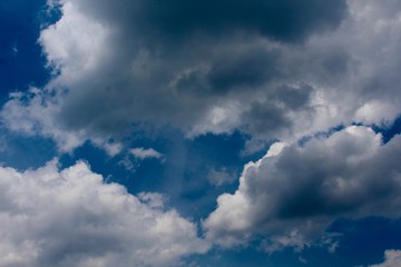 The white and dark clouds in the patchy blue sky.