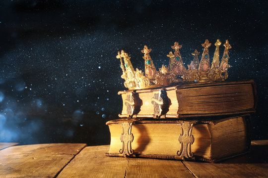 low key of queen/king crown on old books. vintage filtered. fantasy medieval period
