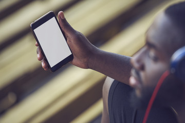 A handsome black man is holding a mock up phone screen, over shoulder view