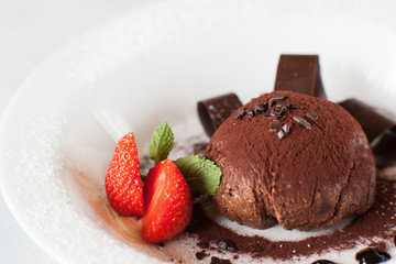 Chocolate fondant on white plate with decoration from strawberry and mint. Delicious dessert serving in restaurant, close up picture