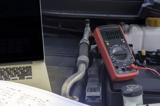Auto mechanic uses a multimeter voltmeter.
