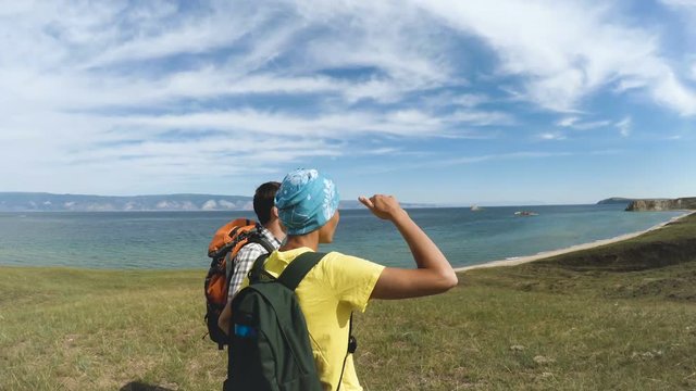 hikers pointing at blue lake. happy hiker couple healthy lifestyle outdoors looking at lake Baikal view.