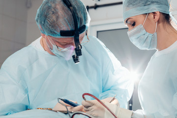 Team of surgeon in uniform perform operation on a patient at plastic surgery clinic