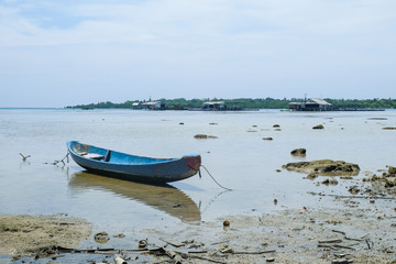 blue drift boat close to an indoensian tropical fisher village