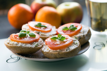 Sandwich with tomato on top at white plate in the glare of the morning sun