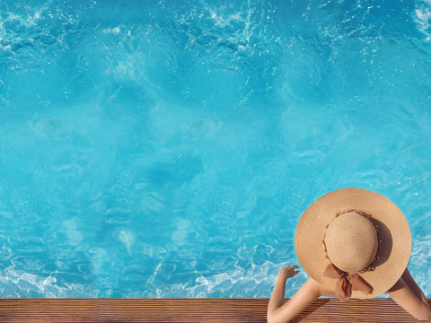 Top view of woman in straw hat relaxing in swimming pool at luxury villa resort. Summer holiday idyllic background. Vacations Concept. Exotic Paradise.