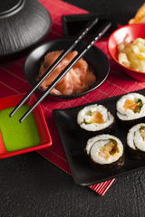 Traditional japanese cuisine - sushi set on red mat and black table