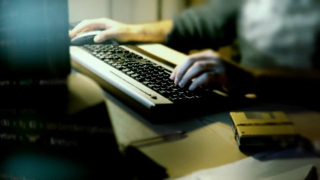 Changing blocks of computer source code, fast zoom-in, angled shots, overlayed on the hands of a man typing on a pc keyboard.
