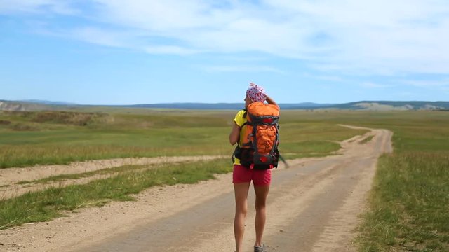 Woman hiker walking along the road near. Travel and active lifestyle concept