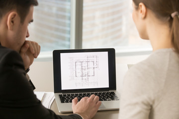 Rear view at architects looking at pc screen while working with scanned copy of building plan,...