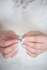 Vertical shot of young Caucasian bride holding a diamond wedding band and an engagement ring with both hands