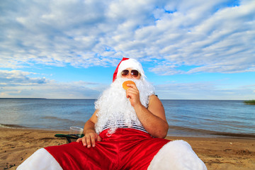 Obraz premium Santa Claus on the beach eating a hamburger.