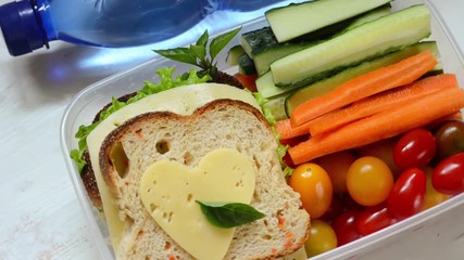 Healthy lunch box with sandwich and fresh vegetables, bottle of water. 