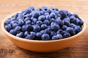 Blueberries in clay bowl. Freshly picked berries on rustic background. Blueberry antioxidant superfood, concept for healthy eating