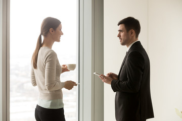 Smiling business team members talking during coffee break, young businessman and businesswoman...