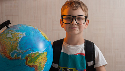 Portrait of little boy with glasses, holding a globe. The nerd with the globe