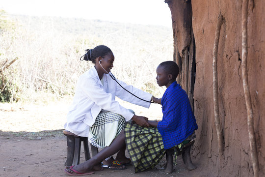 Female Doctor examining female Maasai patient in Maasai village. Kenya, Africa.