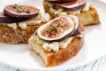 toast with figs and blue cheese on a plate, closeup