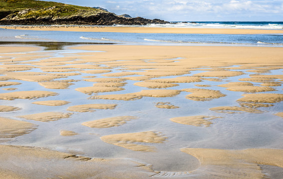 Puddles of water on sandy beach after a tide. © _jure