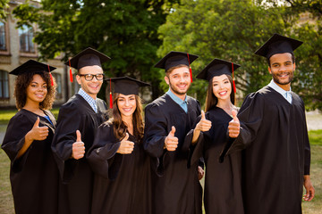 Six successful joyful multi ethnic attractive young graduates in black robes and hats finished...