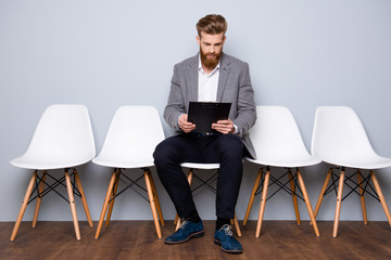 Young man in formalwear with red beard holdyng clipboard with cv and prepare for interview