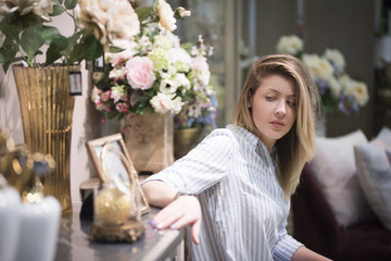 Beautiful girl among the flowers sad looking at the photo in the frame