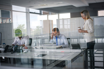 Three business people working in office. Two business people  reading document.