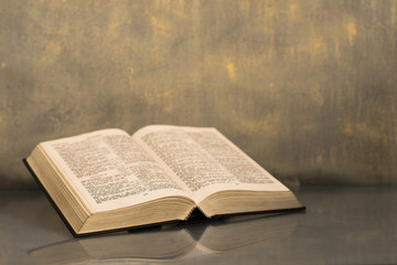 Bible on a glass dark table. Beautiful gold background.Religion concept.