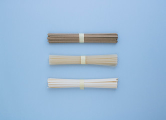 Asian rice noodles, udon and soba on a bright blue background. Minimalism. Flat lay.
