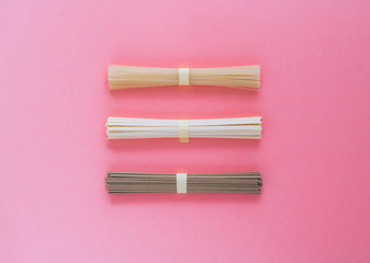 Asian rice noodles, udon and soba on a bright pink background. Minimalism.Flat lay.
