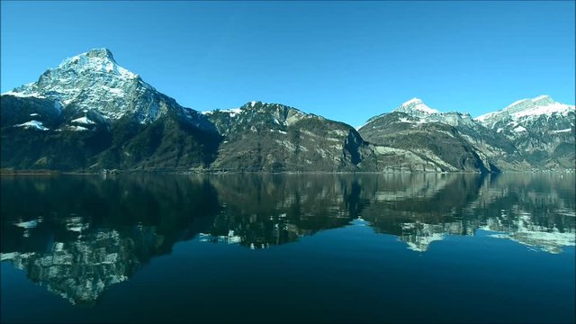 Relaxed morning on the lake in the Alps. The tops of the mountains and white clouds are reflected in the surface of the water, a mirror. 