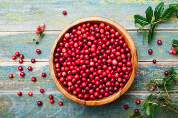 Ripe fresh cowberry (lingonberry, partridgeberry, foxberry) in wooden bowl on rustic vintage table from above.