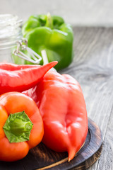 Ripe peppers on wooden board, glass jar, garlic. Canning peppers. Selective focus,close up. 
