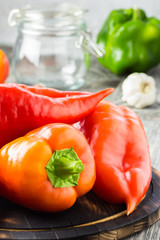 Colorful raw  paprika on wooden board, glass jar. Making pickled peppers. Selective focus,close up, copy space. 