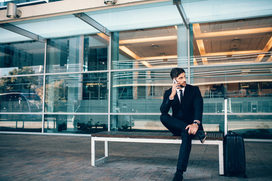 Handsome businessman sitting on bench at airport