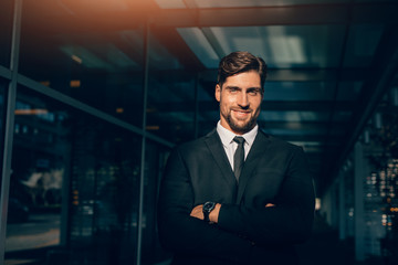 Smiling young businessman standing with his arms crossed