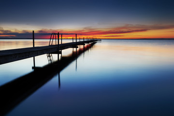 Obraz premium Landing stage by the sea at sunset