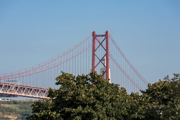 Beautiful view of the red bridge, Ponte 25 de Abril in Lisbon. The bridge connects two cities across the river. Concept of architecture, construction, transportation