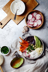 Fresh healthy vegetarian bowl for lunch with baked carrots and red onion, coucous and sliced avocado. Simple and colourful organic food concept. Vertical flat lay with copy space.